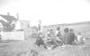 Pauline Bernard and Theresa Googoo watching ball game. others unknown. Membertou Ball field. Eliza Moore's house in background